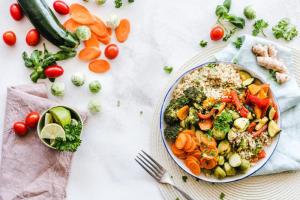 Bol equilibrado con quinoa, verduras asadas y hortalizas frescas alrededor