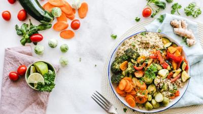 Bol equilibrado con quinoa, verduras asadas y hortalizas frescas alrededor