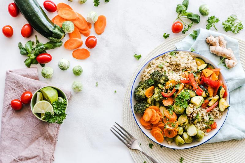Bol equilibrado con quinoa, verduras asadas y hortalizas frescas alrededor