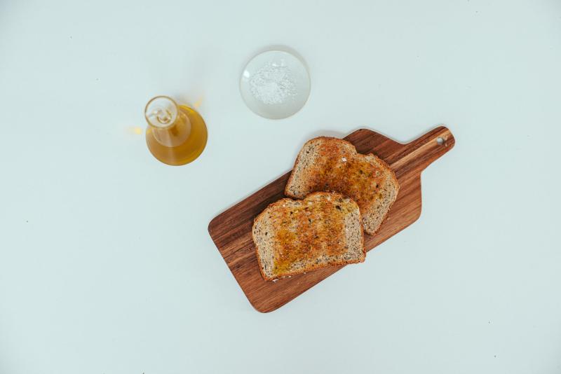 Tostadas de pan integral con aceite de oliva sobre una tabla de madera