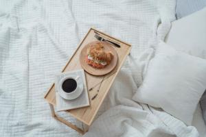 Bandeja de desayuno sencilla con café y bollo, servida en la cama