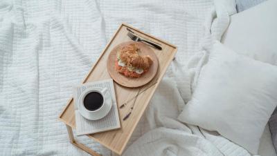 Bandeja de desayuno sencilla con café y bollo, servida en la cama