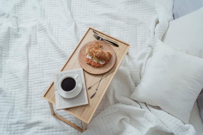 Bandeja de desayuno sencilla con café y bollo, servida en la cama