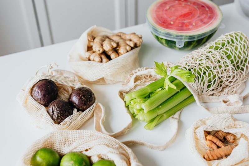 Bolsas reutilizables con frutas y verduras frescas organizadas sobre una mesa