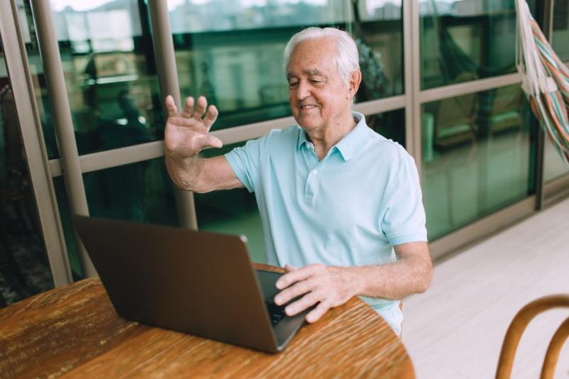 Abuelo sonriendo en una videollamada con el portátil