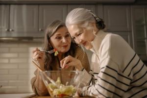 Dos amigas mayores preparando y disfrutando una ensalada juntas en la cocina