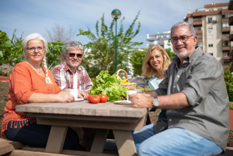 Grupo de amigos mayores sentados a la mesa al aire libre con verduras frescas
