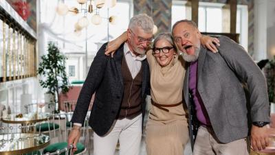 Amigos mayores riendo y abrazándose en una cafetería