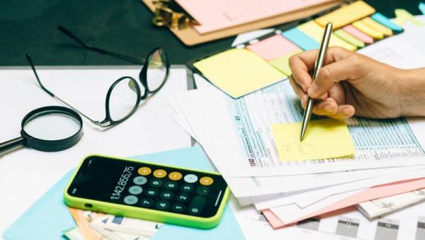 Mesa de escritorio con calculadora, gafas y documentos para la declaración de la renta