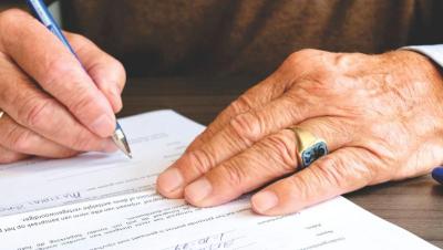 Manos de una persona mayor firmando un documento legal