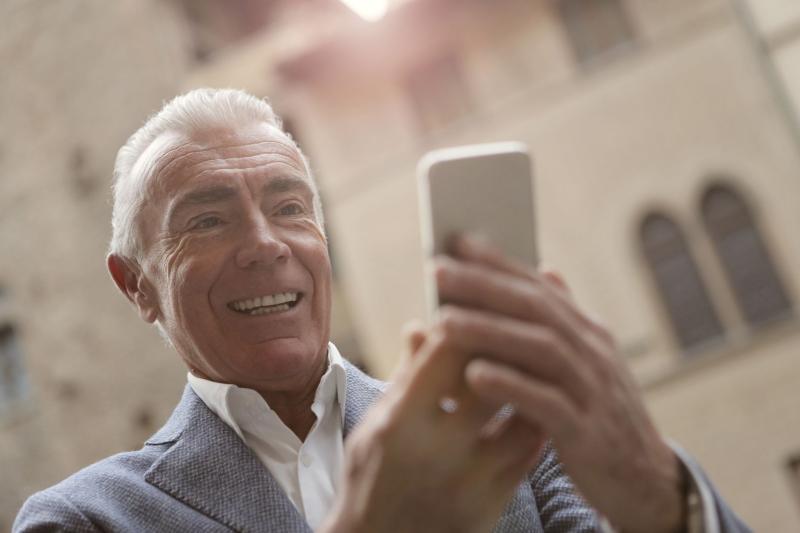 Hombre mayor sonriendo mientras hace una videollamada con el móvil