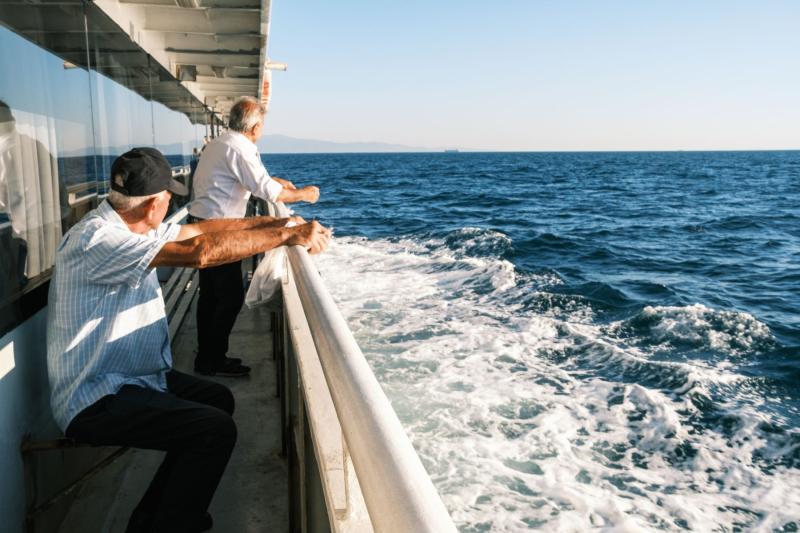 Dos hombres mayores mirando el mar desde la cubierta de un ferry o crucero