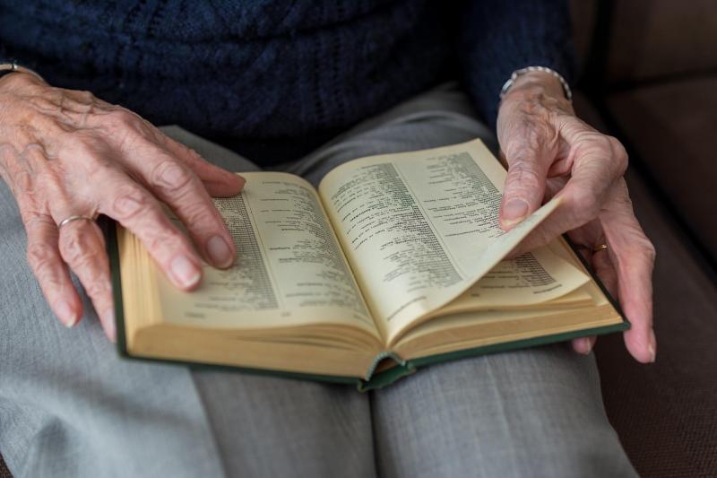 Manos de una persona mayor sosteniendo un libro abierto
