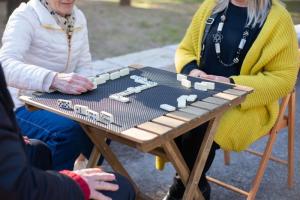 Personas mayores jugando al dominó en una mesa exterior
