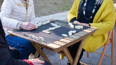 Personas mayores jugando al dominó en una mesa exterior