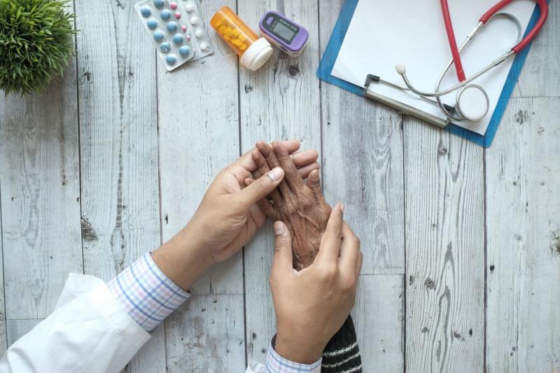 Manos de un médico sosteniendo con cariño la mano de un paciente mayor