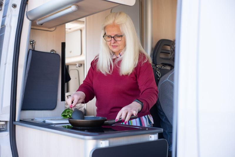 Mujer mayor cocinando dentro de una autocaravana
