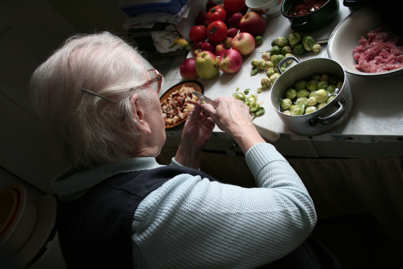 Mujer mayor preparando verduras frescas en su cocina