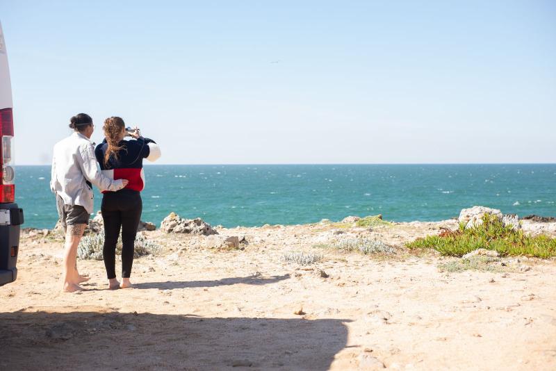 Pareja mayor junto a su autocaravana con vistas al mar en Portugal