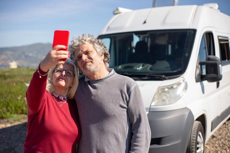 Pareja mayor haciéndose una foto frente a su autocaravana
