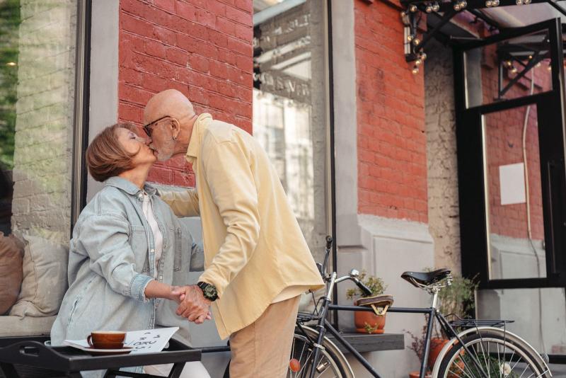Pareja mayor compartiendo un beso romántico junto a una cafetería