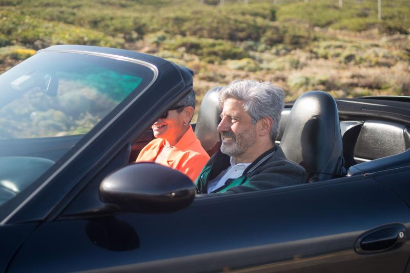 Pareja mayor sonriendo en un coche descapotable durante una escapada