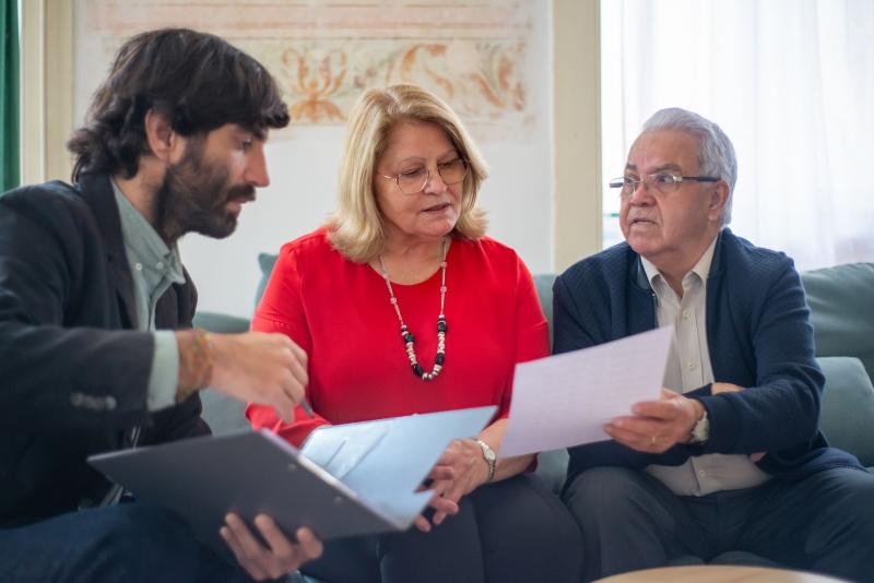 Pareja de personas mayores consultando documentos con un asesor financiero