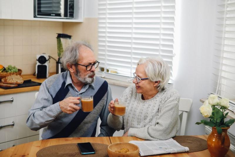 Pareja mayor desayunando y tomando café juntos en la cocina de casa