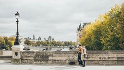 Pareja mayor paseando con su perro por un puente de París