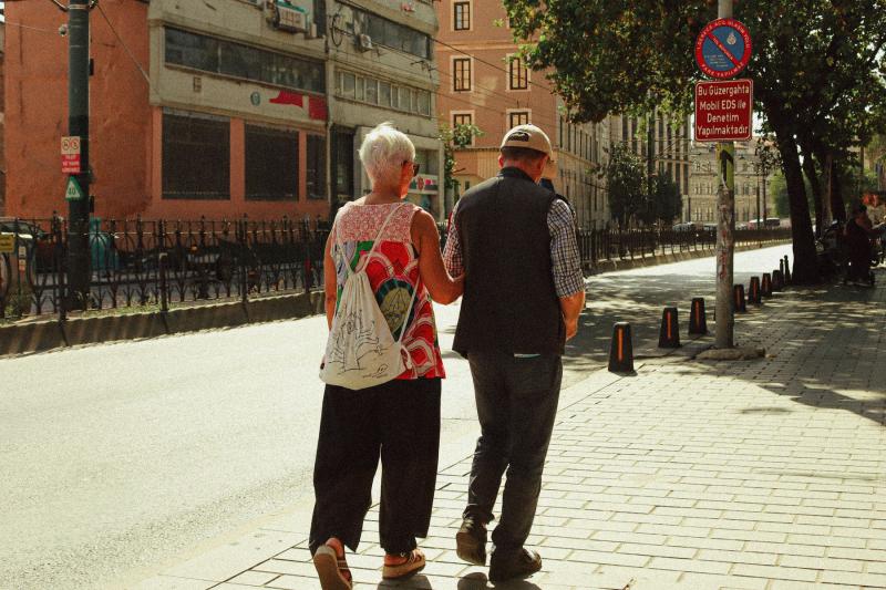 Pareja de personas mayores paseando del brazo por una calle de la ciudad durante un viaje