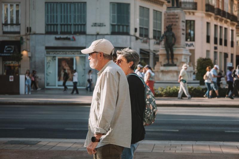 Pareja mayor paseando por una plaza en España