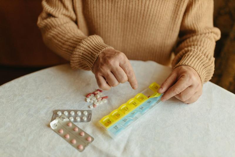 Manos de una persona mayor organizando un pastillero semanal
