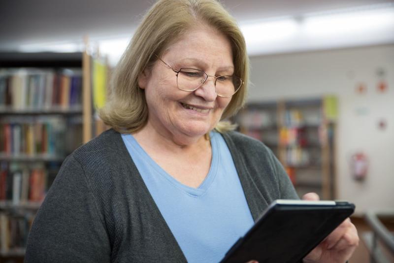 Mujer mayor sonriendo mientras usa una tablet
