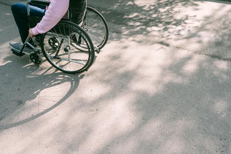 Persona en silla de ruedas desplazándose por una carretera soleada