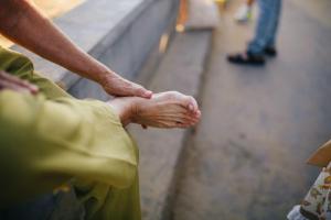 Manos de una persona mayor masajeando su pie descalzo al aire libre