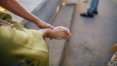 Manos de una persona mayor masajeando su pie descalzo al aire libre