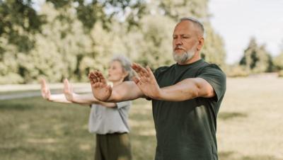 Pareja de personas mayores practicando tai chi al aire libre en un parque