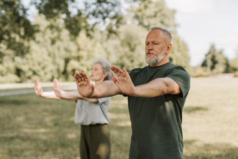 Pareja de personas mayores practicando tai chi al aire libre en un parque