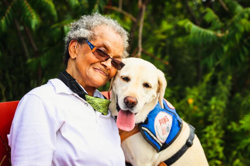 Mujer mayor abrazando con cariño a un perro de terapia al aire libre