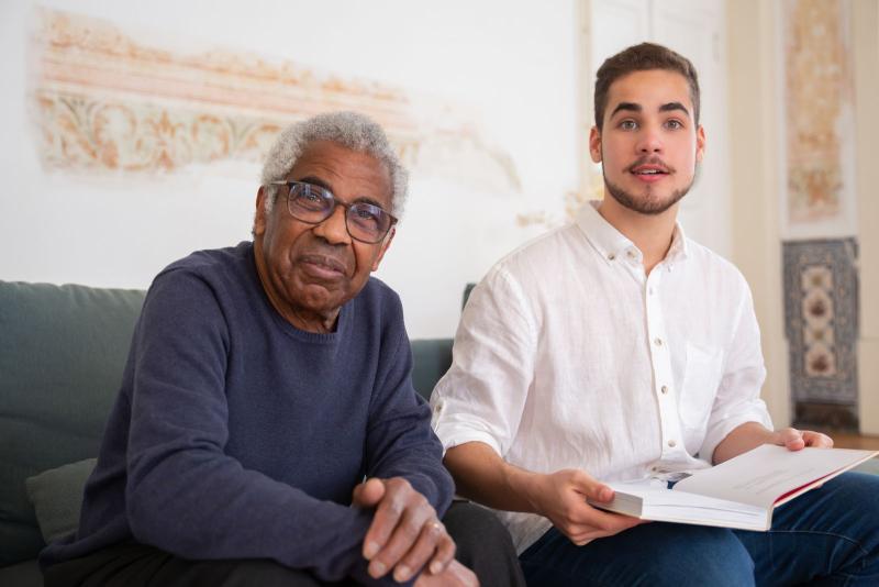 Hombre mayor leyendo junto a un joven