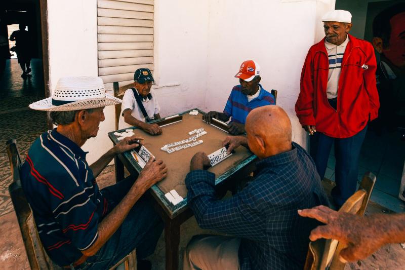 Grupo de hombres mayores jugando al dominó en una terraza