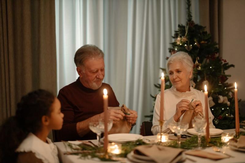 Pareja de abuelos y su nieta en la mesa de la cena de Navidad